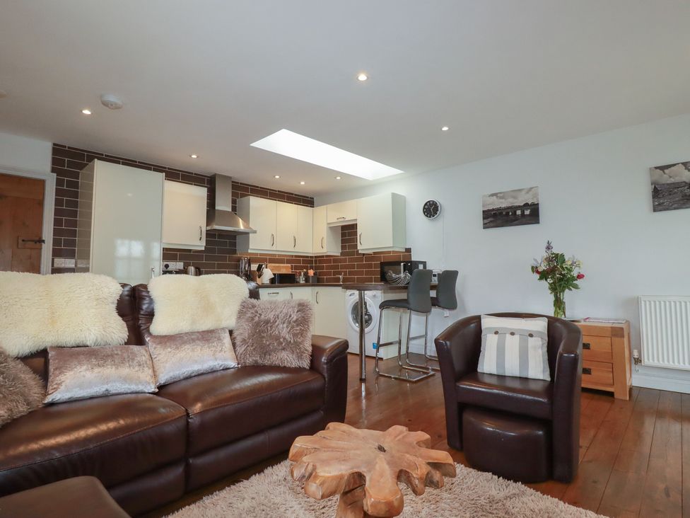 A living room with a sofa and kitchen area at The Smithy in Blisland