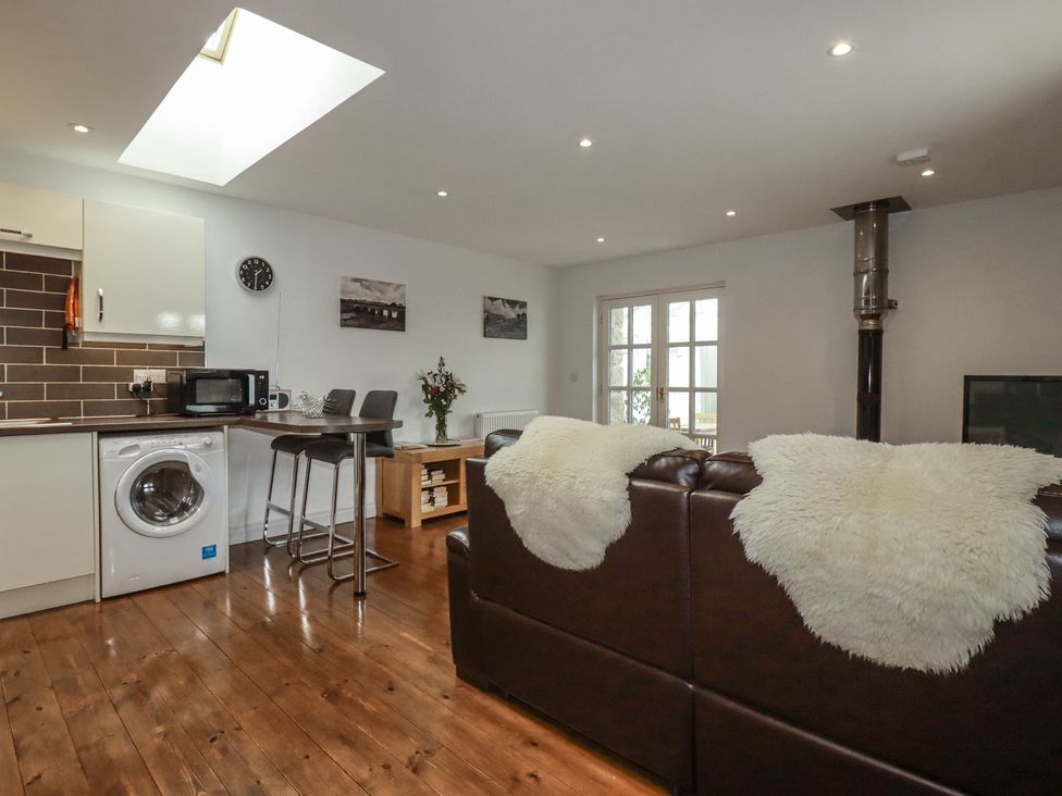 A living room with a washing machine and bar stools at The Smithy in Blisland
