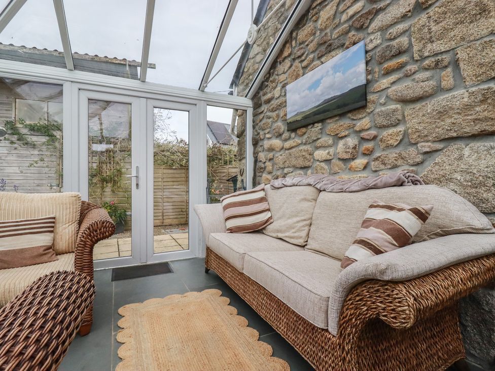 A conservatory with a sofa and rug at The Smithy in Blisland