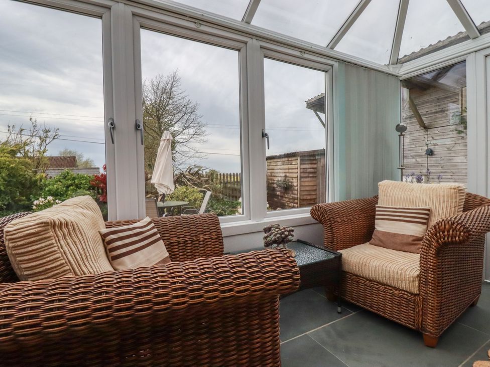A conservatory with seating and views of the garden at The Smithy in Blisland