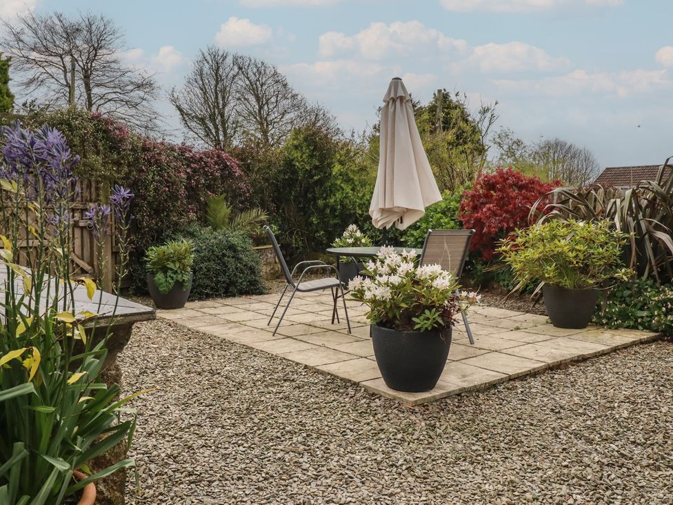 A garden with a table and chairs with an umbrella at The Smithy in Blisland