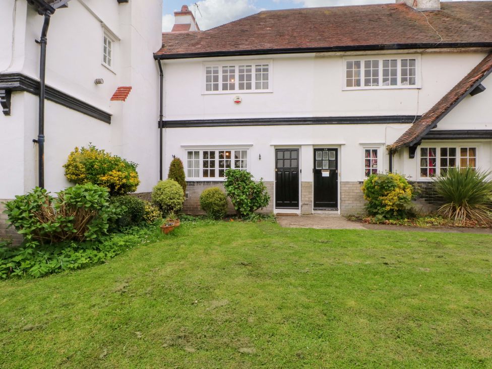 A garden with a building featuring doors and windows at Sunlight Soap Cottage in Port Sunlight