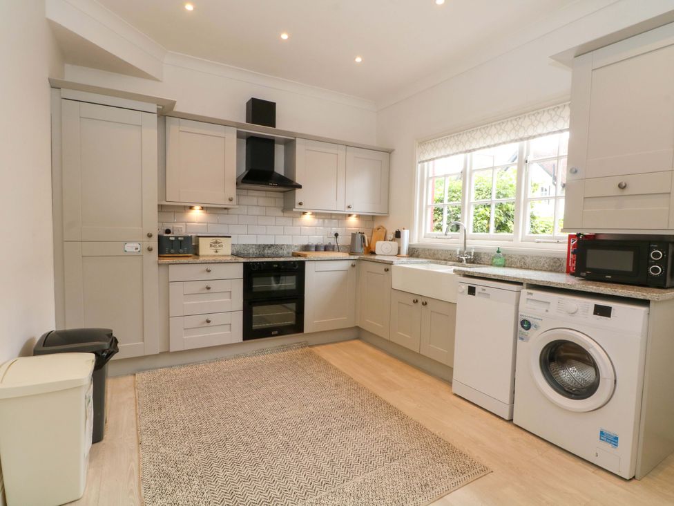 A kitchen with cabinets, sink, oven, washer, and microwave at Sunlight Soap Cottage Port Sunlight