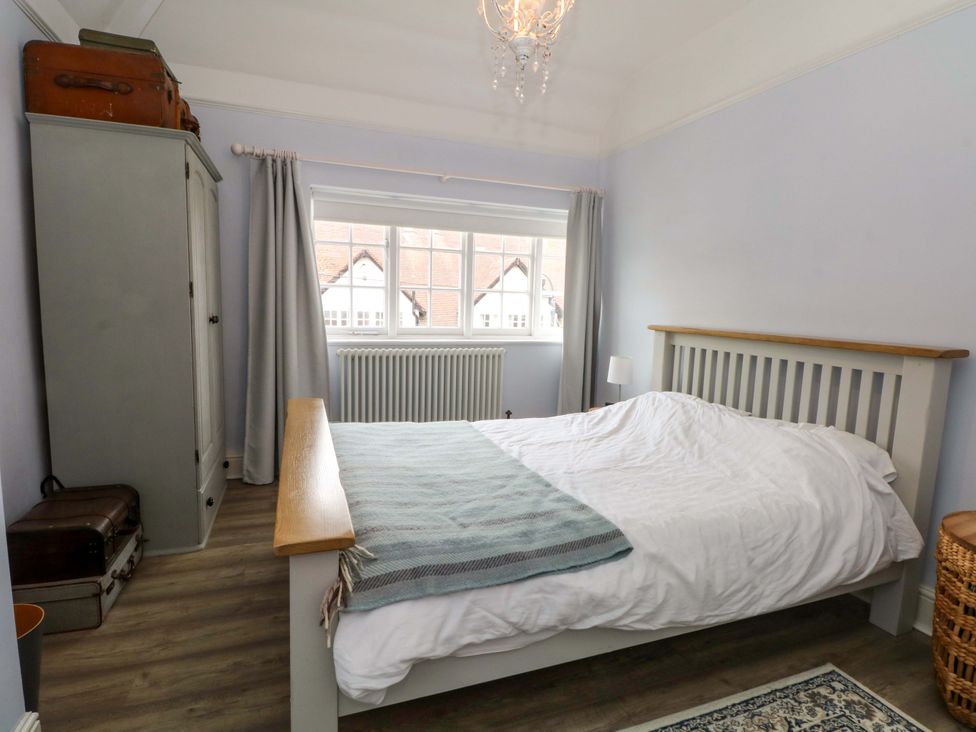 A bedroom with a bed, wardrobe, and window at Sunlight Soap Cottage in Port Sunlight