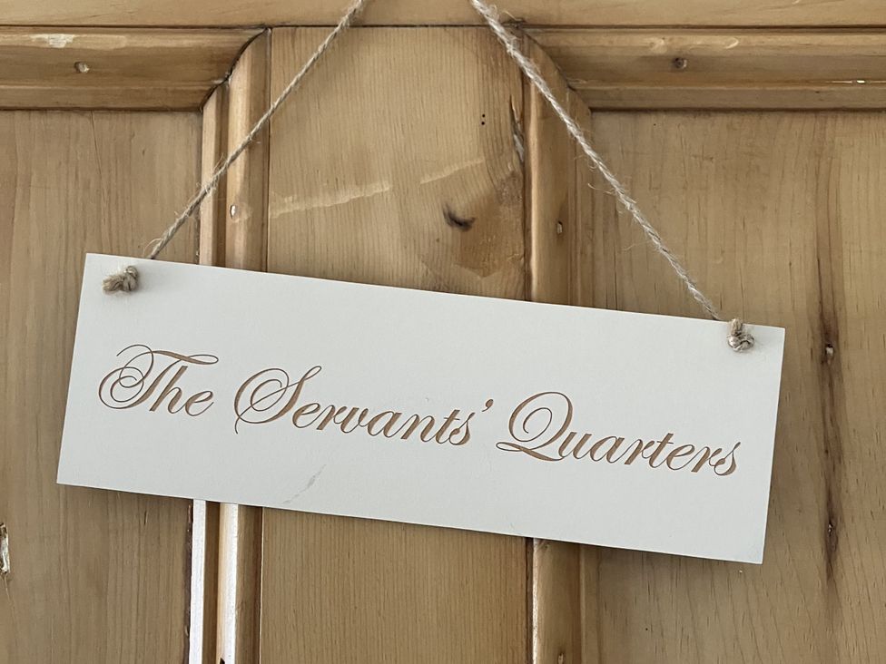A sign hanging on a wooden door indicating The Servants' Quarters at Godscroft Hall in Frodsham
