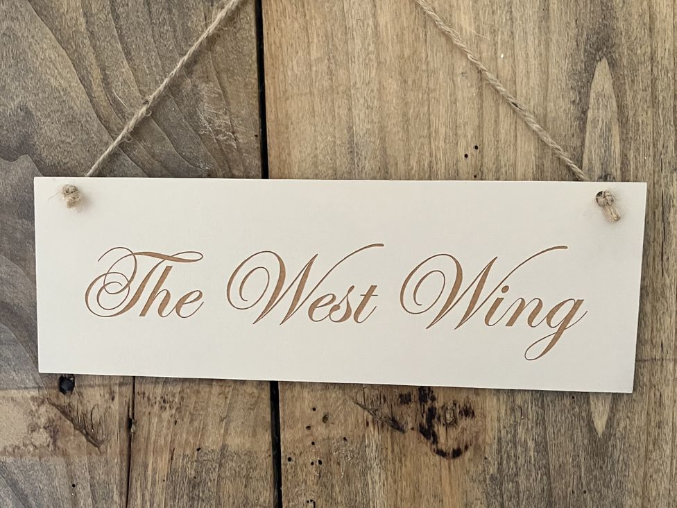A sign labeled The West Wing on wooden surface at Godscroft Hall in Frodsham