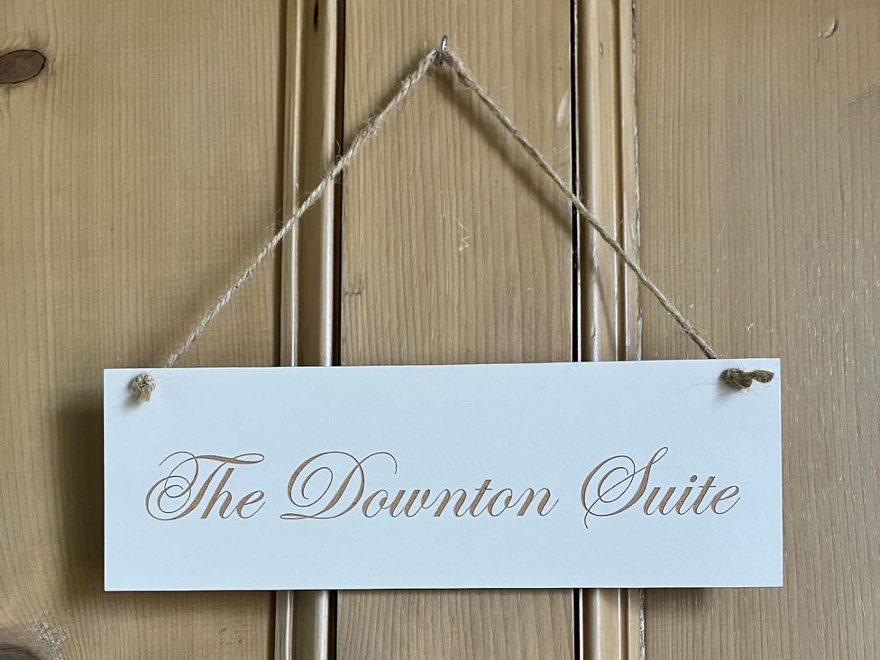 A sign for The Downton Suite on wooden panel at Godscroft Hall in Frodsham