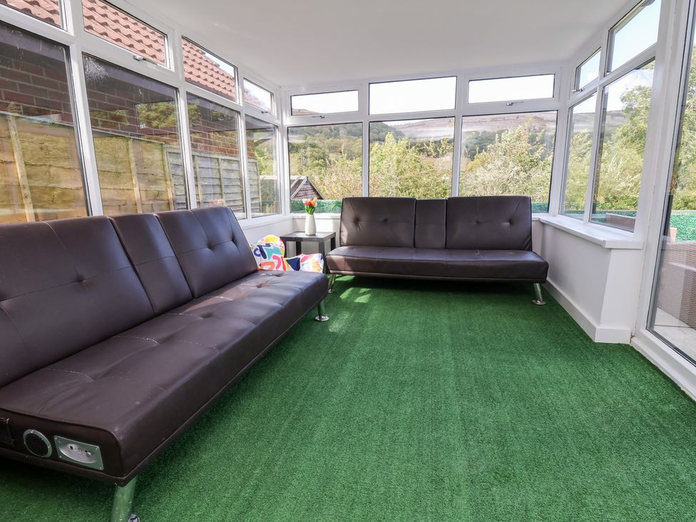 A conservatory with sofas and a coffee table at Talgais in Llangollen