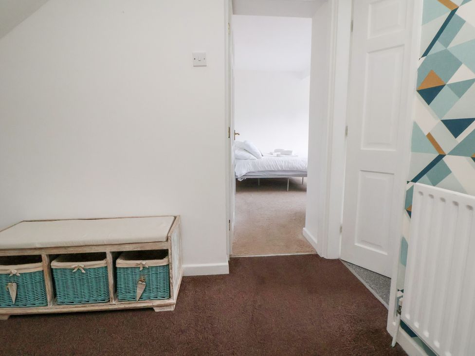 A hallway with a storage bench and a view of a bedroom at Talgais in Llangollen