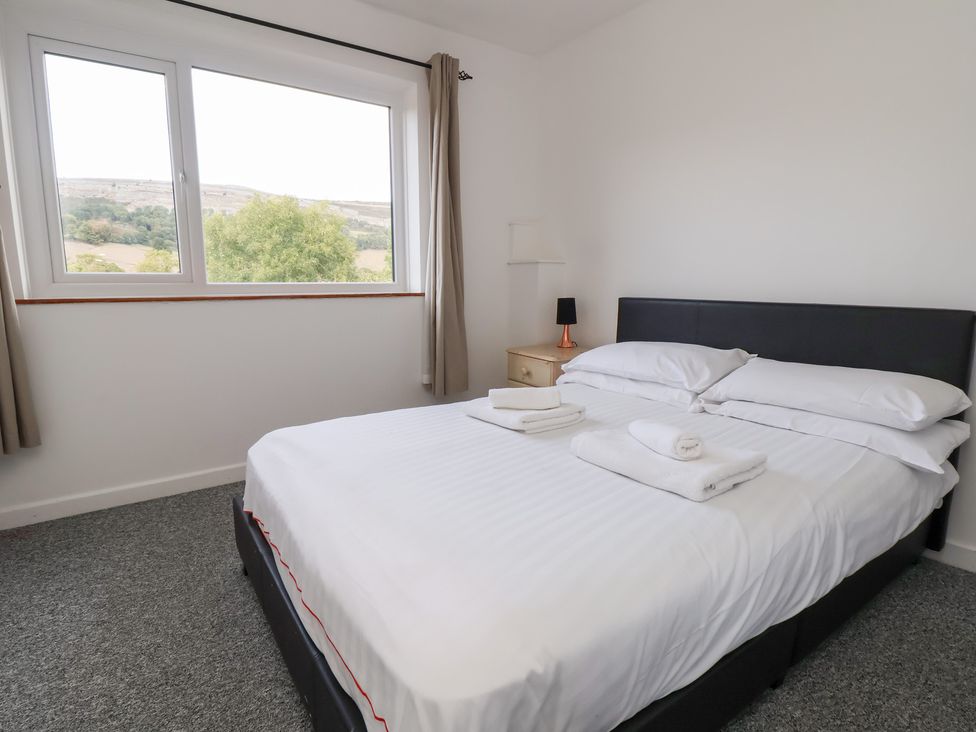 A bedroom with a bed and side table at Talgais in Llangollen