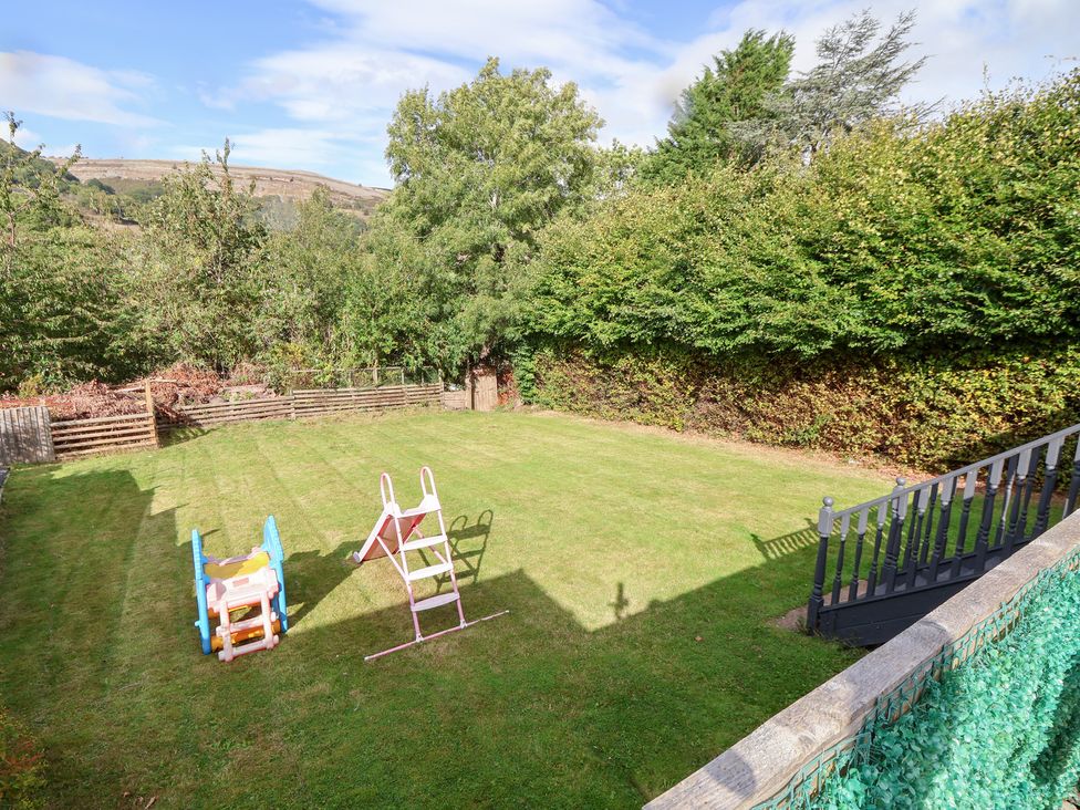 A garden with a playhouse and a slide at Talgais in Llangollen