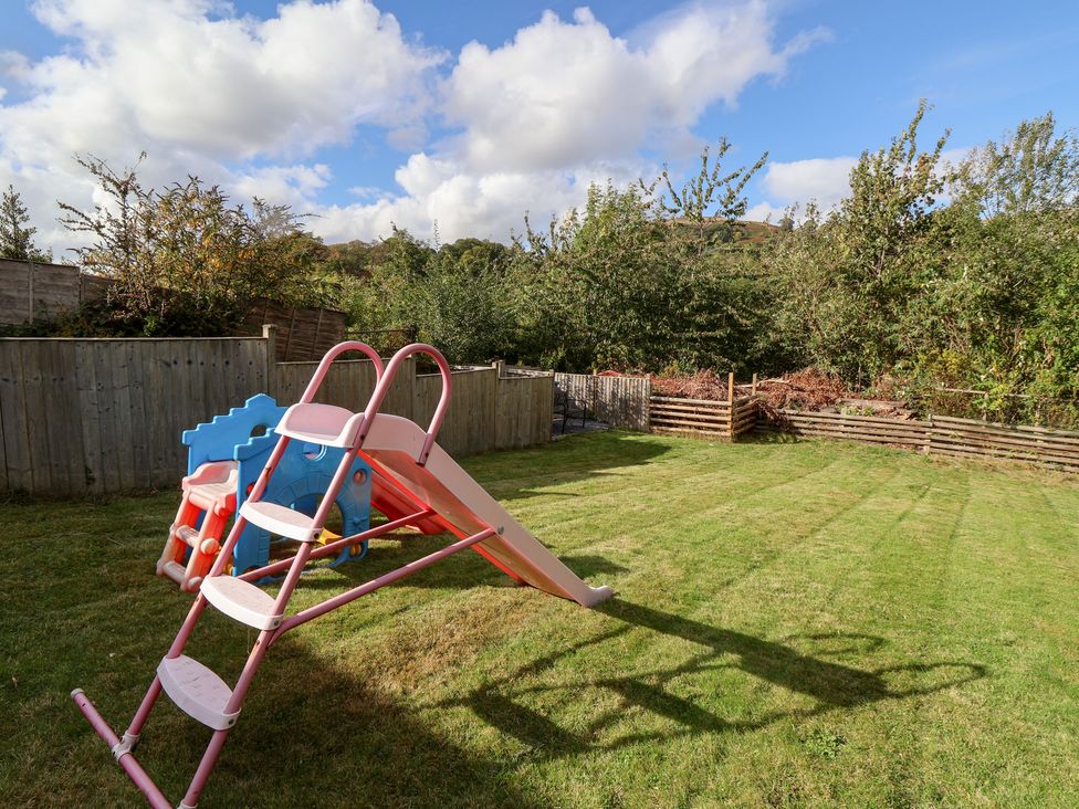 A garden with a slide and playhouse at Talgais in Llangollen