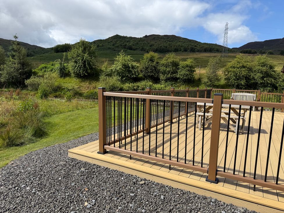 An outdoor area with a decking, table, and chairs at Burnside Lodge (Lodge 1, Glengoulandie) Aberfeldy