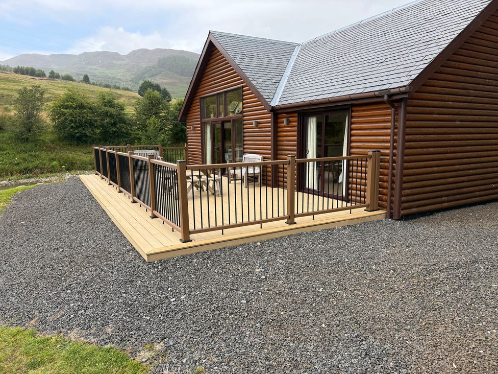 A log cabin with decking and chairs at Burnside Lodge (Lodge 1, Glengoulandie) Aberfeldy