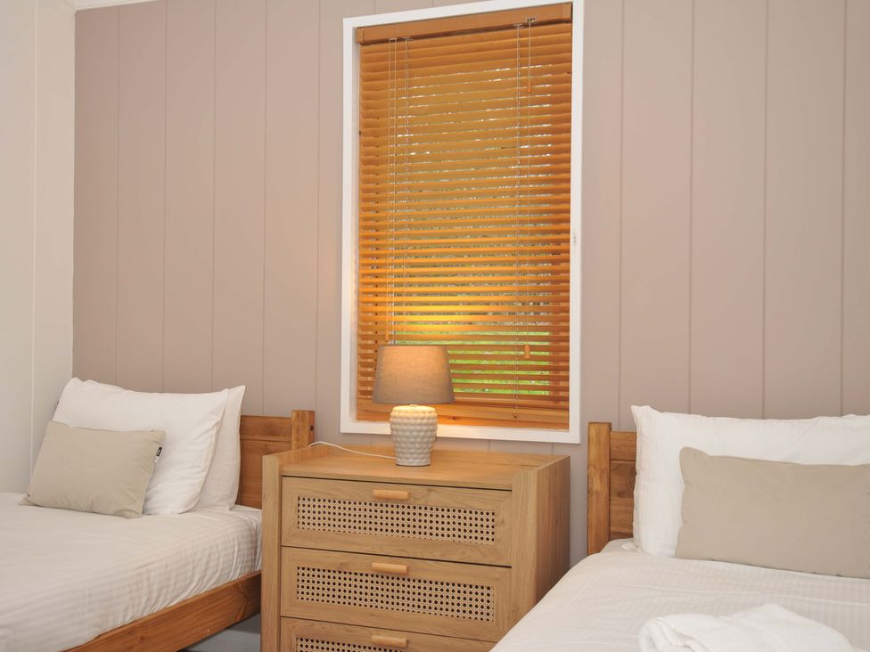 A bedroom with two beds and a lamp on a nightstand at 6 Hedgerows, Lanreath