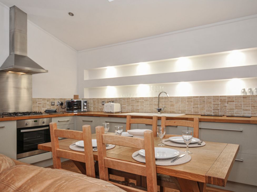 A kitchen with a dining table and chairs at 2 Streamside in Looe