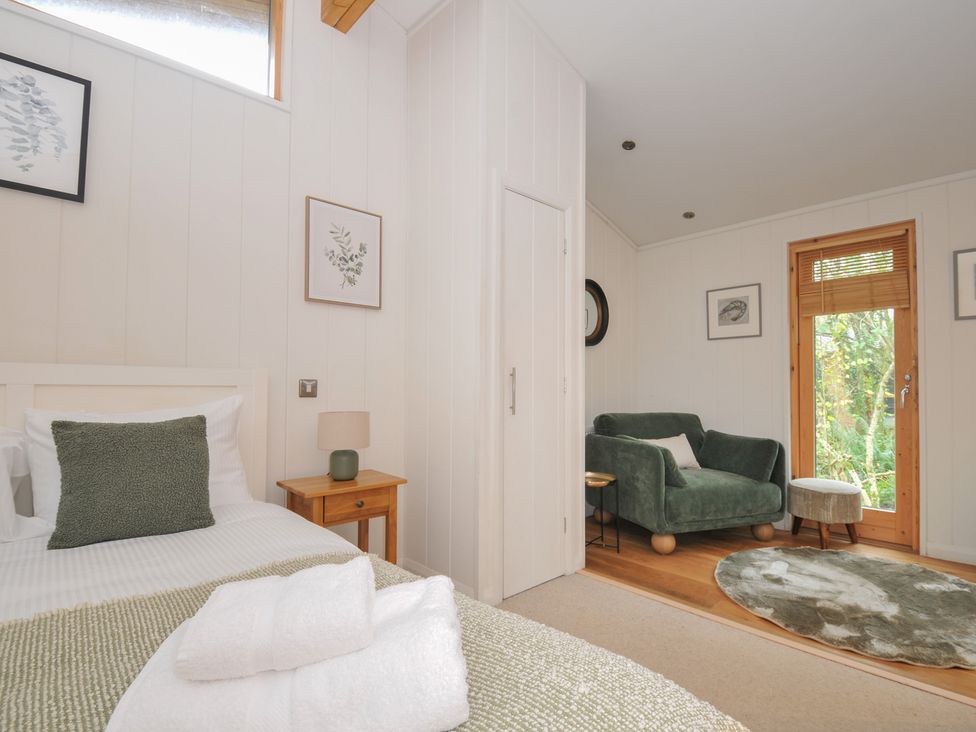 A bedroom with a bed and seating area at 2 Streamside Looe