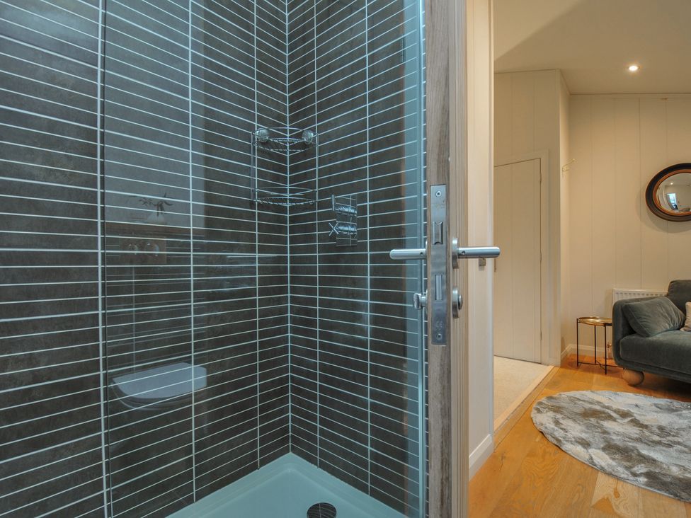 A shower with glass door and tiled wall at 2 Streamside Looe