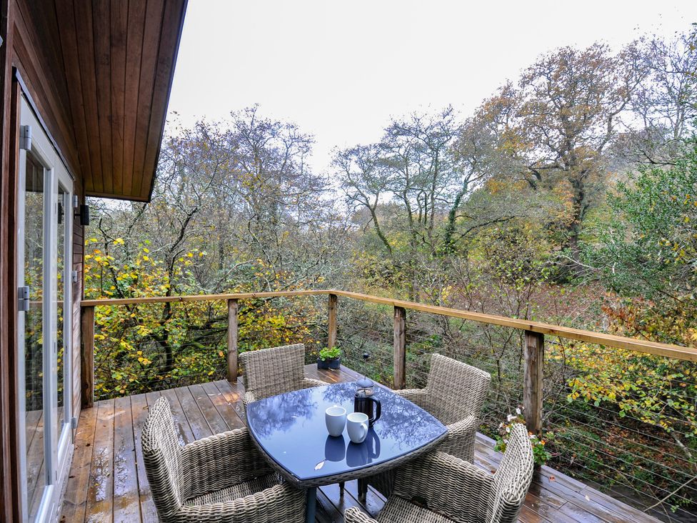 An outdoor area with a table and chairs overlooking trees at 2 Streamside Looe