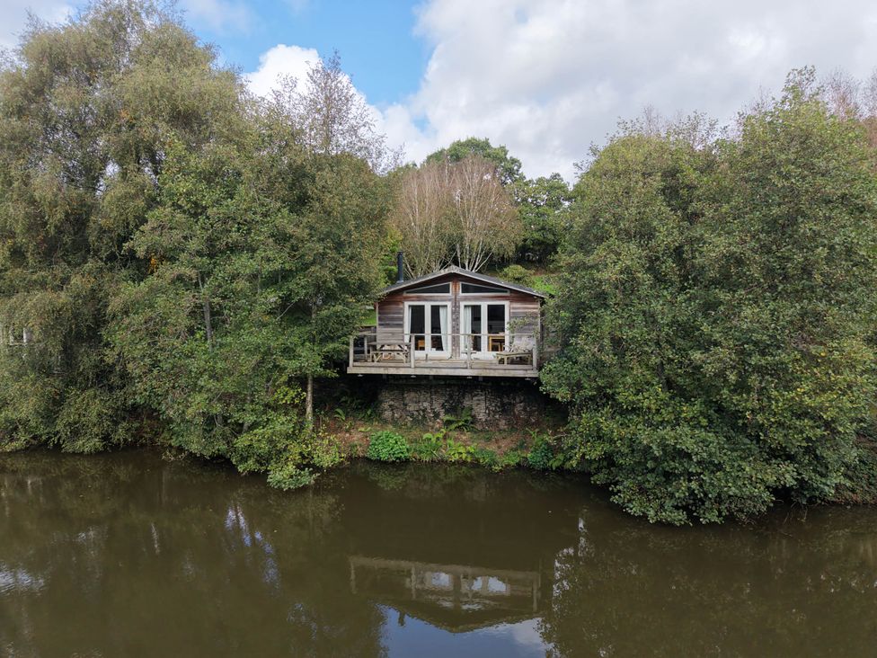 A wooden cabin on the edge of a river at 2 Water's Edge in Lanreath