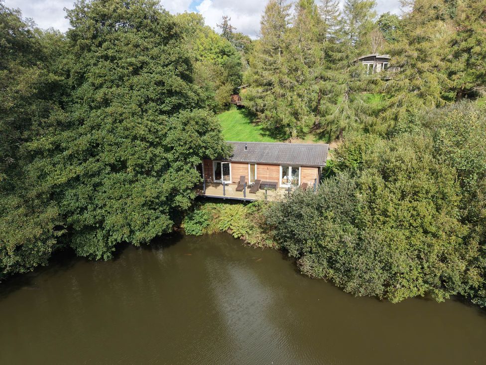 A cabin near a river with trees surrounding it at 6 Water's Edge in Lanreath