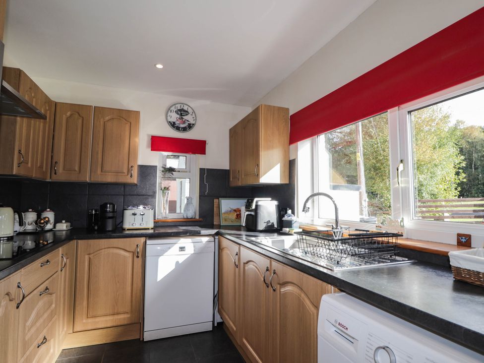 A kitchen with wooden cupboards and appliances at St. Aethans in Bonar Bridge