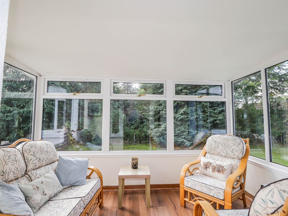 A conservatory with seating and windows at St. Aethans in Bonar Bridge