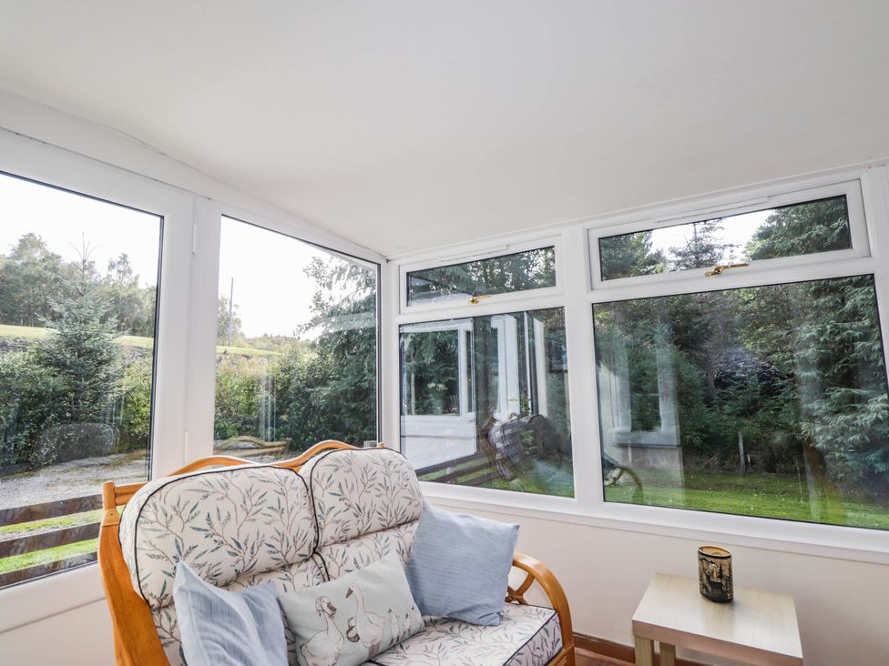 A conservatory with a sofa and a table at St. Aethans in Bonar Bridge