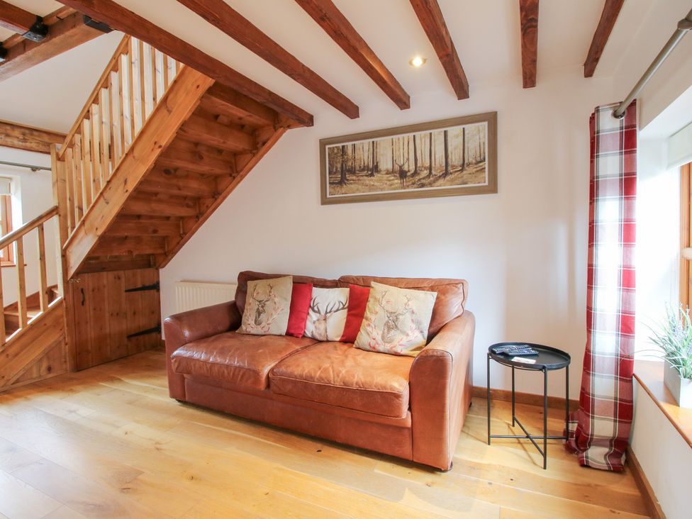 A living room with a sofa and staircase at Old Hall Barn 4 Church Stretton