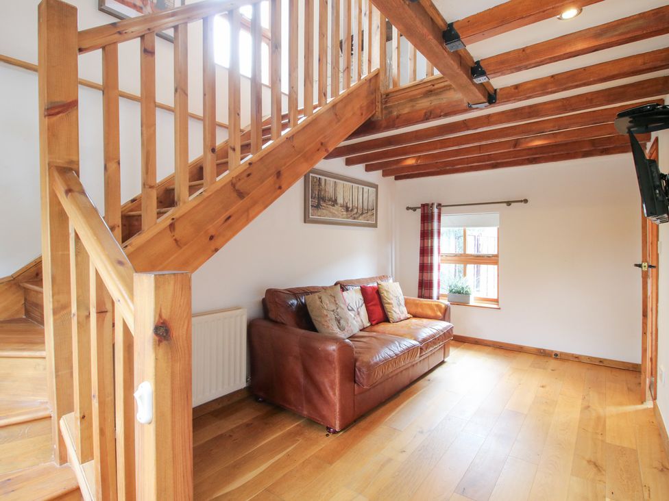 A living room with a staircase and sofa at Old Hall Barn 4 Church Stretton