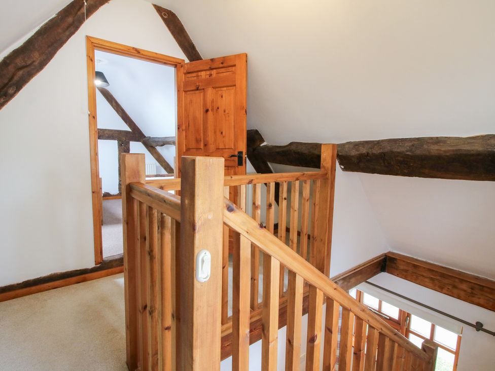 A hallway with wooden railing and door at Old Hall Barn 4 Church Stretton