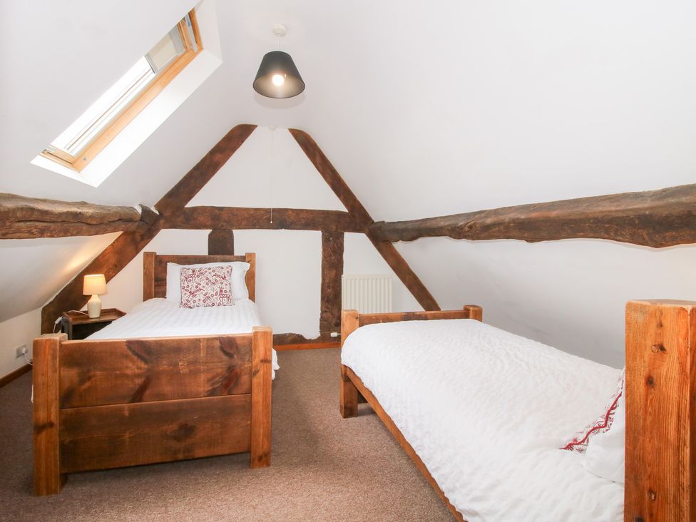 A bedroom with two beds and a window at Old Hall Barn 4, Church Stretton