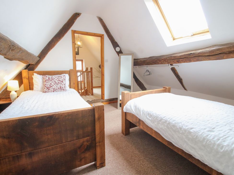 A bedroom with two single beds and a mirror at Old Hall Barn 4 Church Stretton
