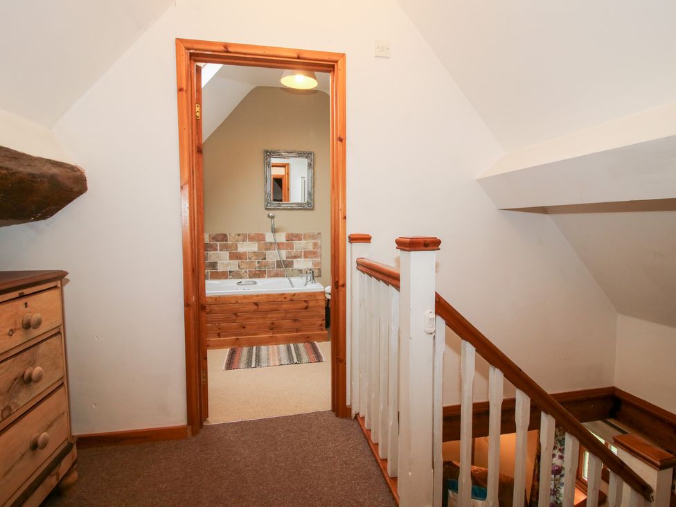 A staircase leading to a bathroom with a bathtub and mirror at Old Hall Barn 4, Church Stretton