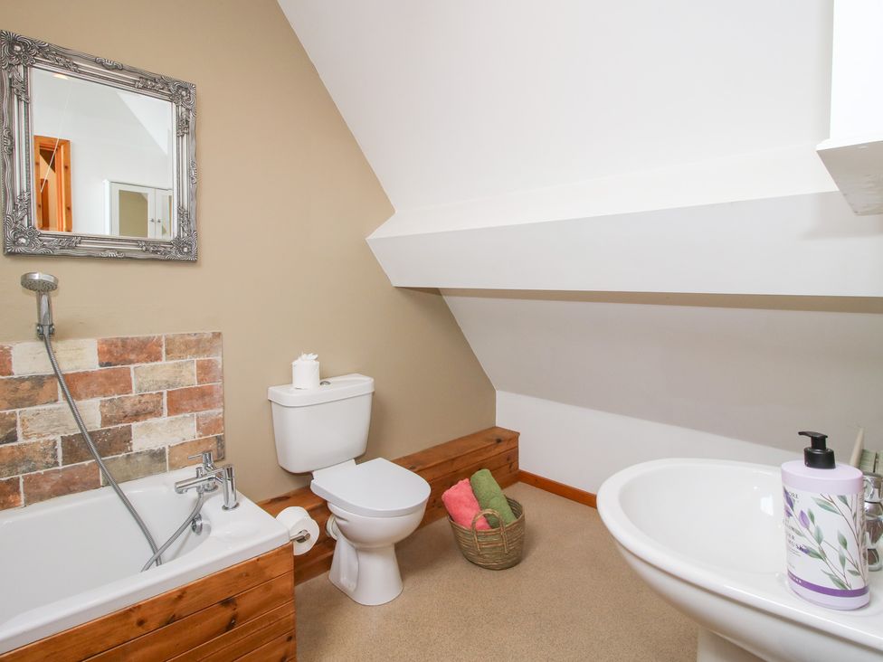 A bathroom with a bathtub, toilet, and sink at Old Hall Barn 4, Church Stretton