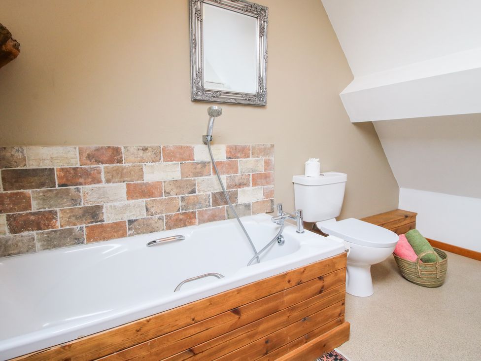 A bathroom with a bathtub and toilet at Old Hall Barn 4 Church Stretton