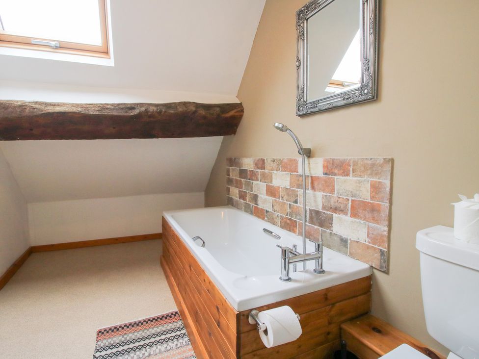 A bathroom with a bathtub and toilet at Old Hall Barn 4, Church Stretton