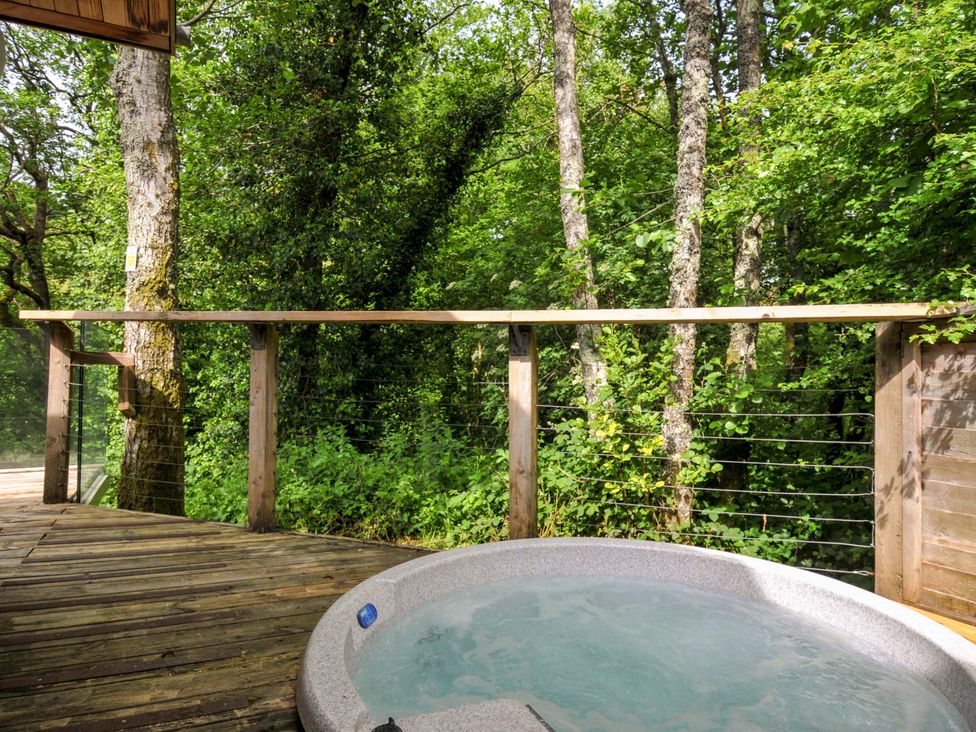 An outdoor hot tub on a wooden deck surrounded by trees at 14 Stonerush Valley, Lanreath