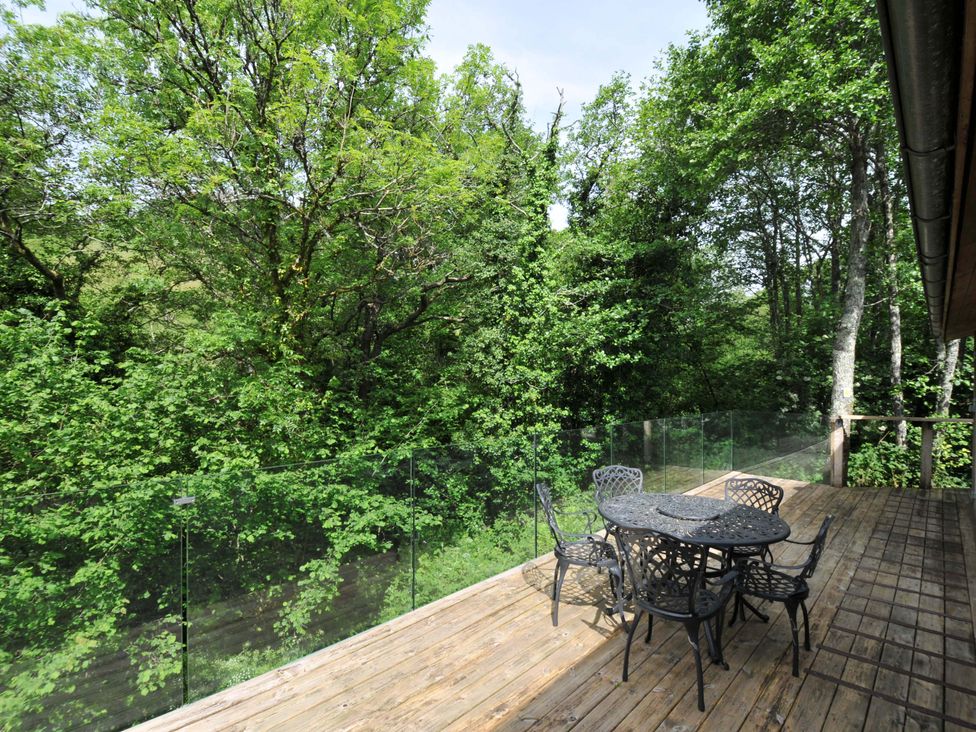 An outdoor area with a table and chairs overlooking trees at 14 Stonerush Valley Lanreath