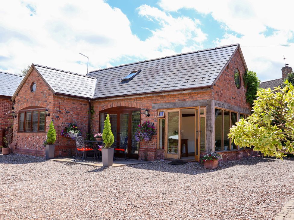 A house with windows and a patio at Honeysuckle Farmhouse in Tarporley