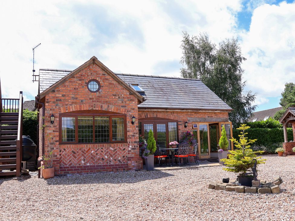 An exterior view of a house with garden furniture at Honeysuckle Farmhouse Tarporley