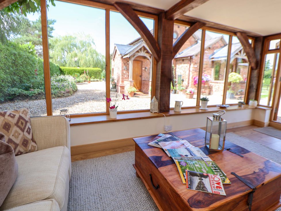 A conservatory with a sofa and coffee table at Honeysuckle Farmhouse in Tarporley