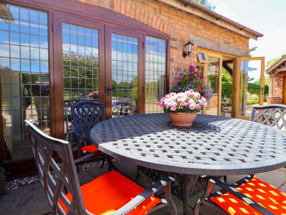 An outdoor dining area with a table and chairs at Honeysuckle Farmhouse Tarporley