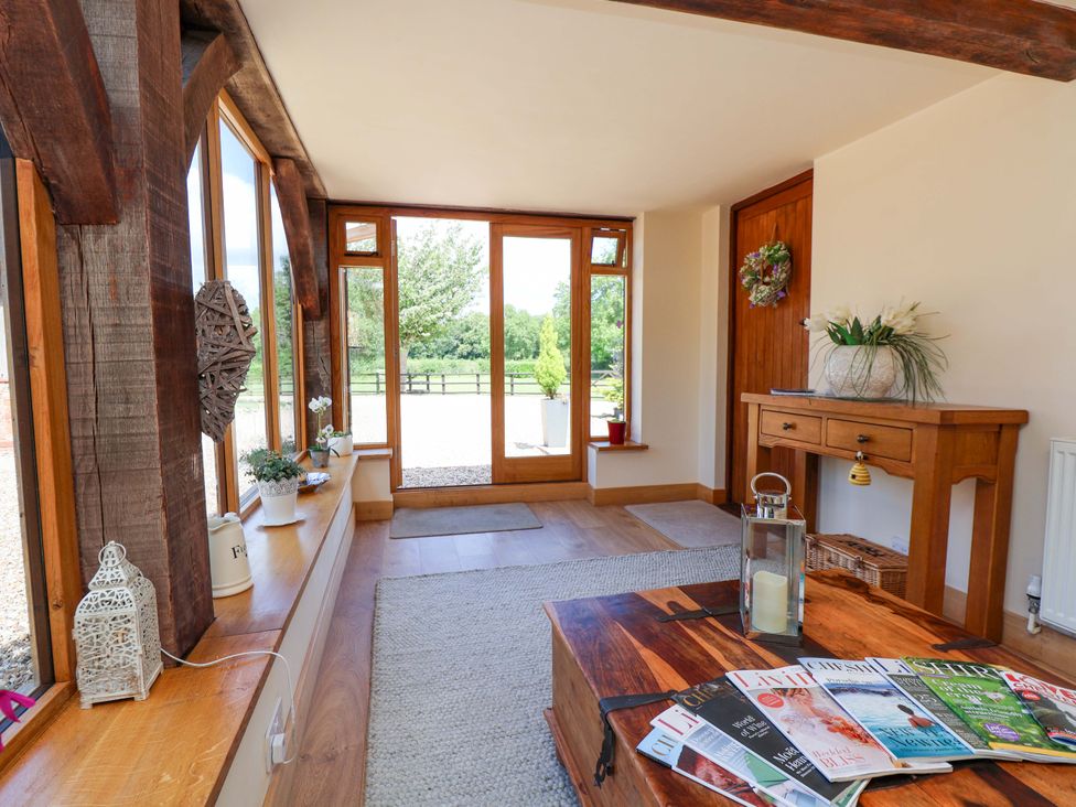 An entrance with a wooden table and magazines at Honeysuckle Farmhouse in Tarporley