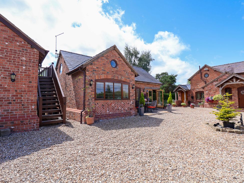 A brick house with steps and gravel driveway at Honeysuckle Farmhouse in Tarporley