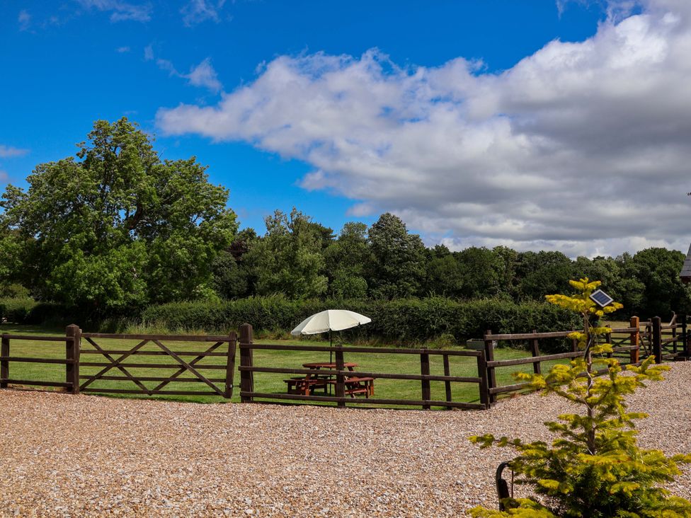 An outdoor area with a picnic table under an umbrella at Honeysuckle Farmhouse in Tarporley