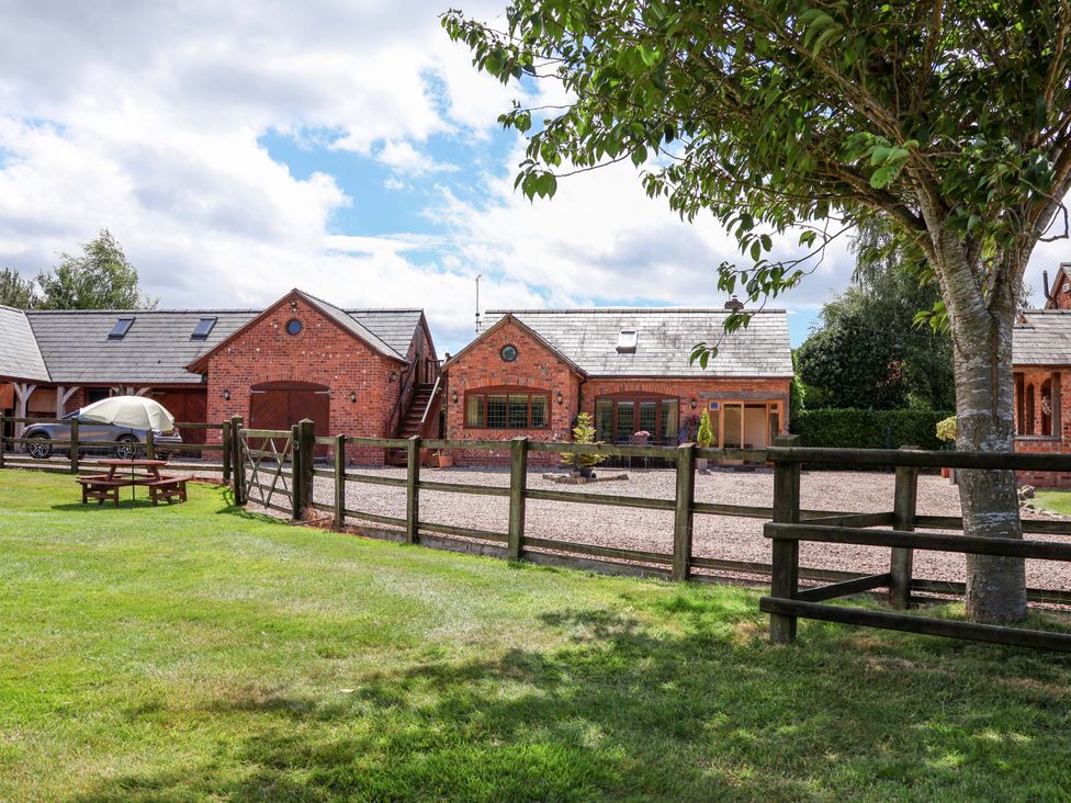A property with a fence and outdoor seating area at Honeysuckle Farmhouse in Tarporley