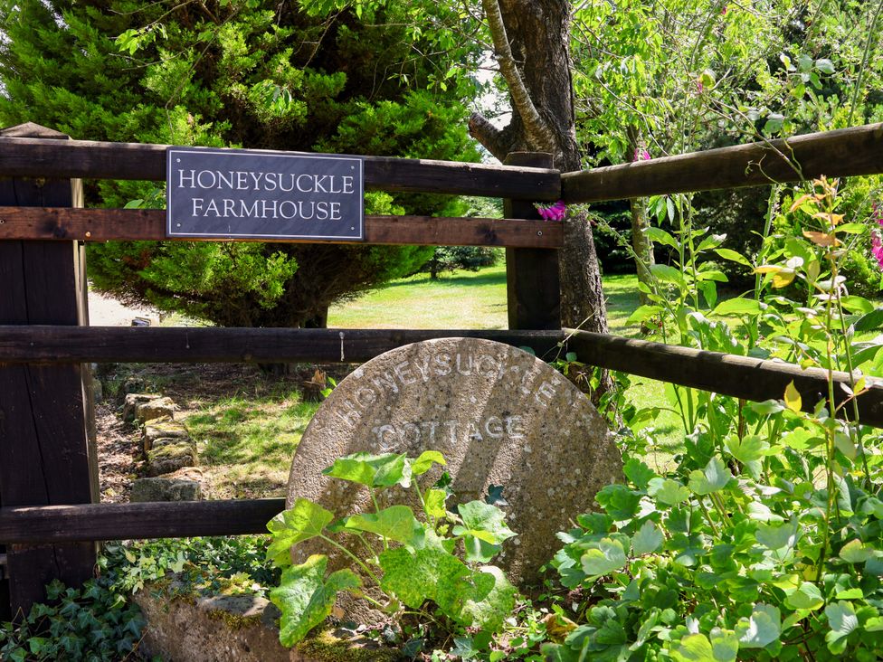 A sign indicating Honeysuckle Farmhouse with plants at Honeysuckle Farmhouse in Tarporley