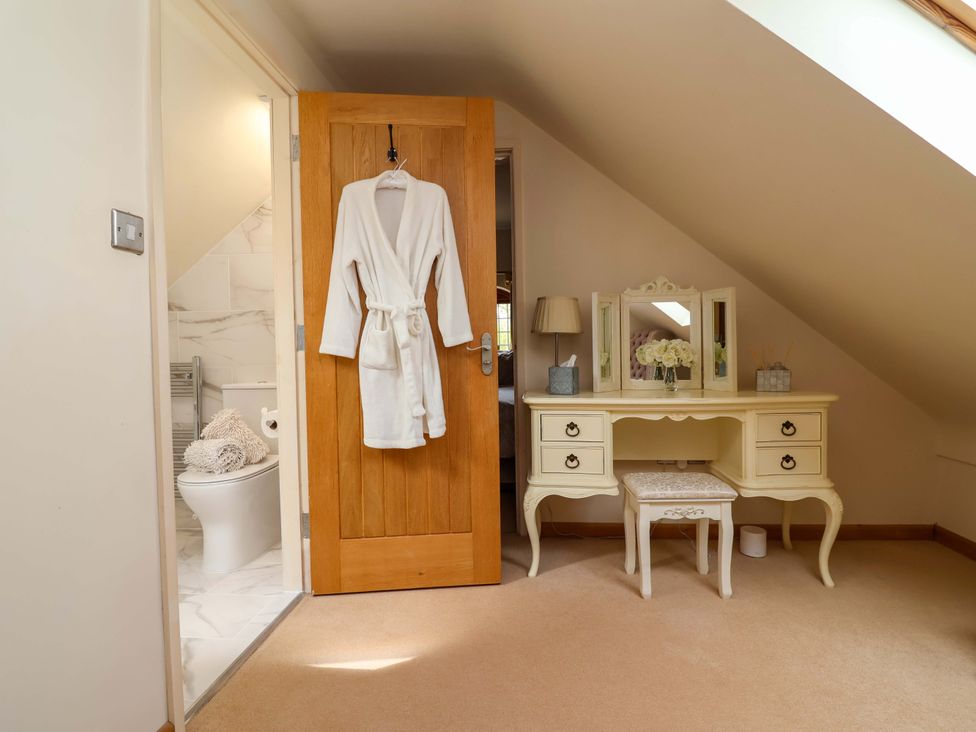 A bedroom with a robe hanging on the door and a vanity at Honeysuckle Farmhouse in Tarporley