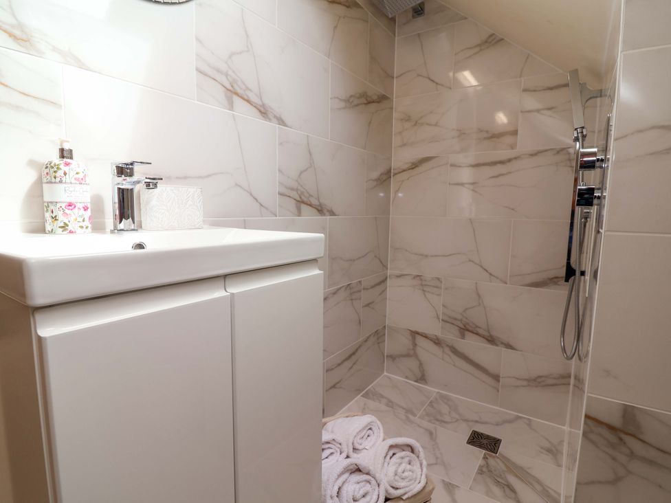A bathroom with a shower and sink at Honeysuckle Farmhouse Tarporley
